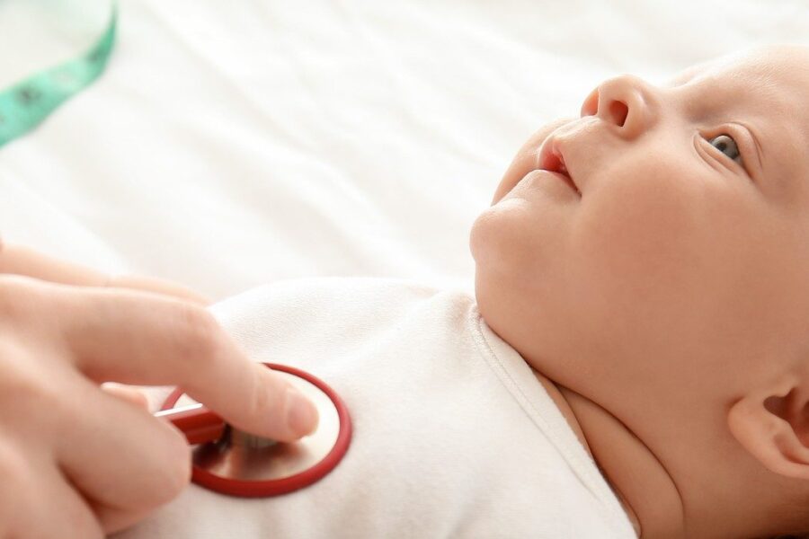 Pediatrician examining cute baby in clinic, closeup