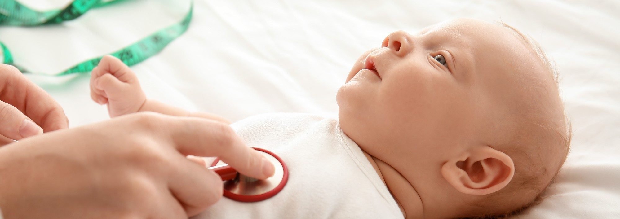Pediatrician examining cute baby in clinic, closeup